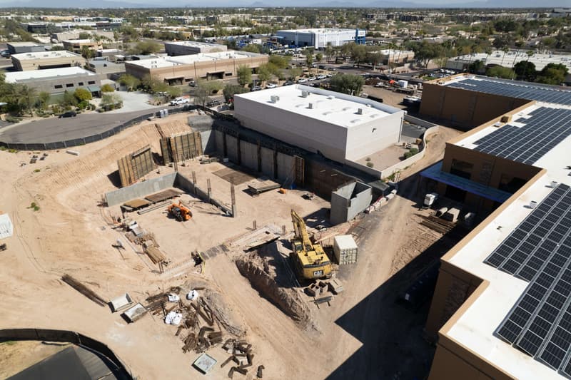 Aerial view of a deep excavation with concrete retaining walls and an excavator on a Diamond West commercial project in Arizona