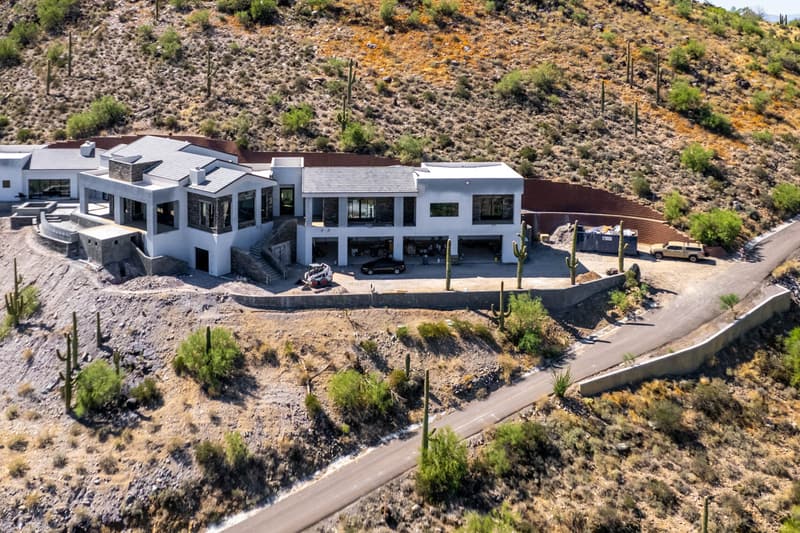 Aerial view of a hillside home site with concrete retaining walls along the pad and driveway, a Diamond West project in Arizona